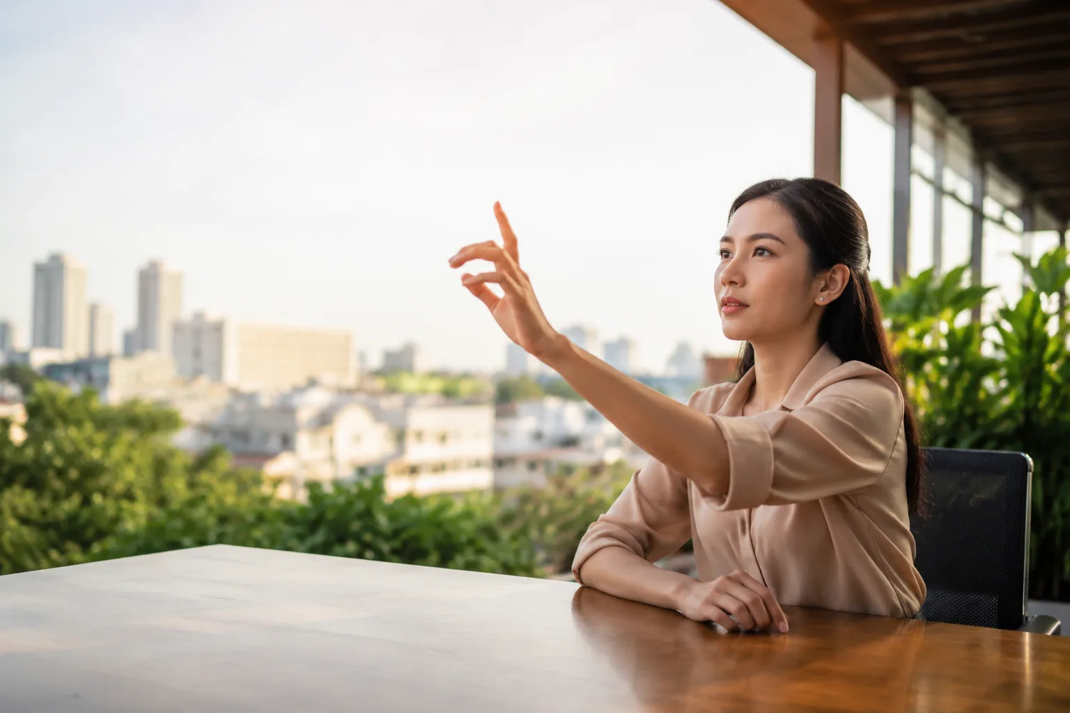 Nhân viên doanh nghiệp Việt Nam ngồi một mình tại bàn làm việc ngoài trời văn phòng, dùng tay chỉ vào không gian trước mặt như đang hình dung hành trình người dùng
