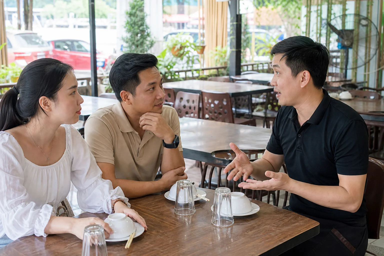 Nhân viên nhà hàng Việt Nam đang trao đổi trực tiếp với nhóm khách về cách sắp xếp bữa ăn trong không gian dùng bữa, thể hiện quá trình xác nhận nhu cầu trước khi tổ chức đoàn