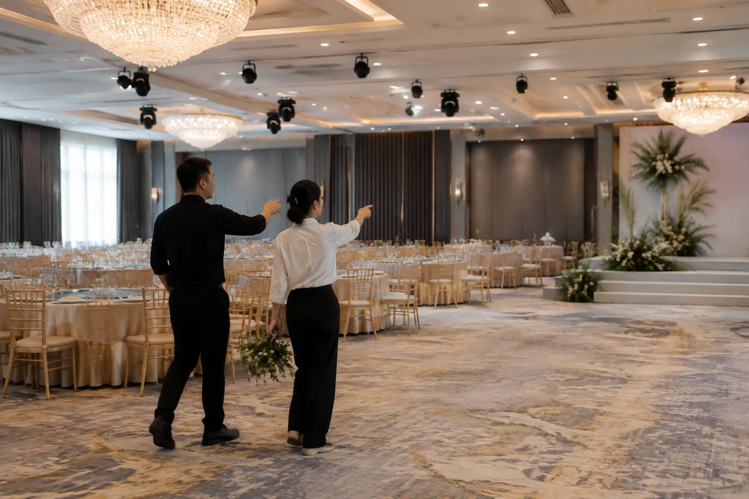Nhân viên nhà hàng Việt Nam cùng chuyên viên trang trí thử hình dung vị trí các điểm nhấn trong sảnh cưới qua việc quan sát không gian thực tế, thể hiện sự phối hợp giữa bố cục sản