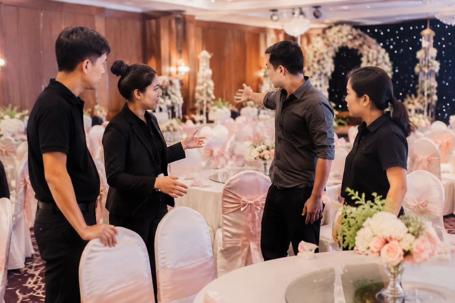 Nhân viên nhà hàng và đơn vị trang trí tại Việt Nam kiểm tra cách sắp xếp các khu vực trong sảnh tiệc cưới, thể hiện quá trình phối hợp để tránh không gian thiếu đồng bộ.