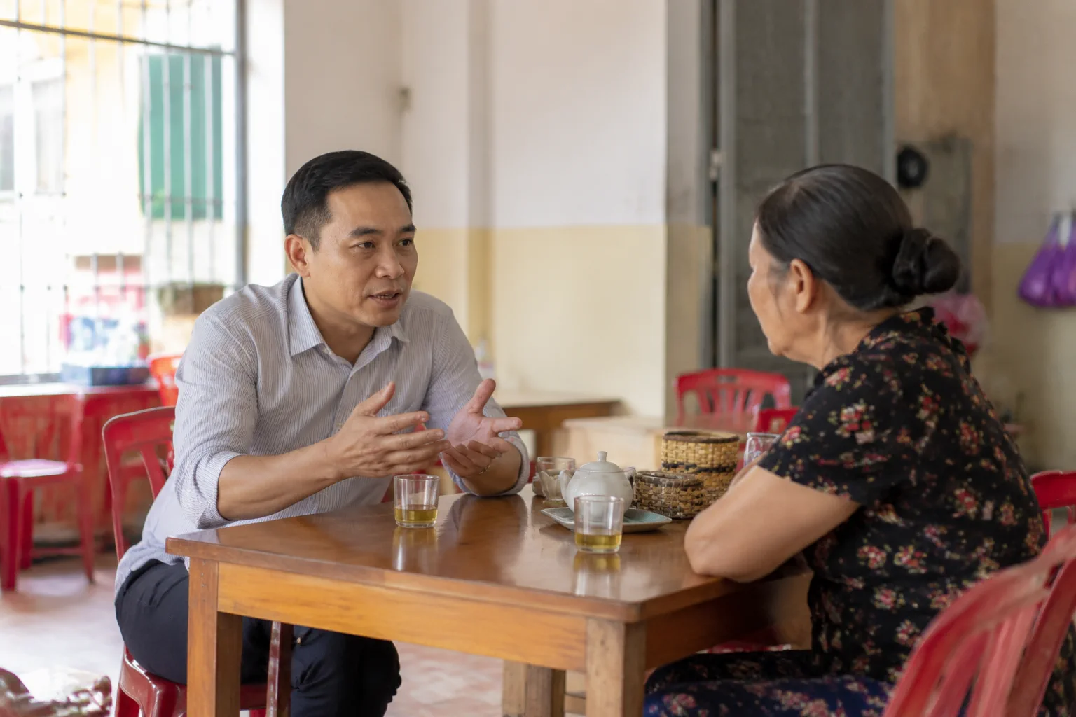 Nhân viên hỗ trợ và người dân đang trao đổi trực tiếp về việc chuẩn bị thông tin cho giao dịch bất động sản tại Đắk Nông trong không gian tư vấn gần gũi, thể hiện bước xác minh trư