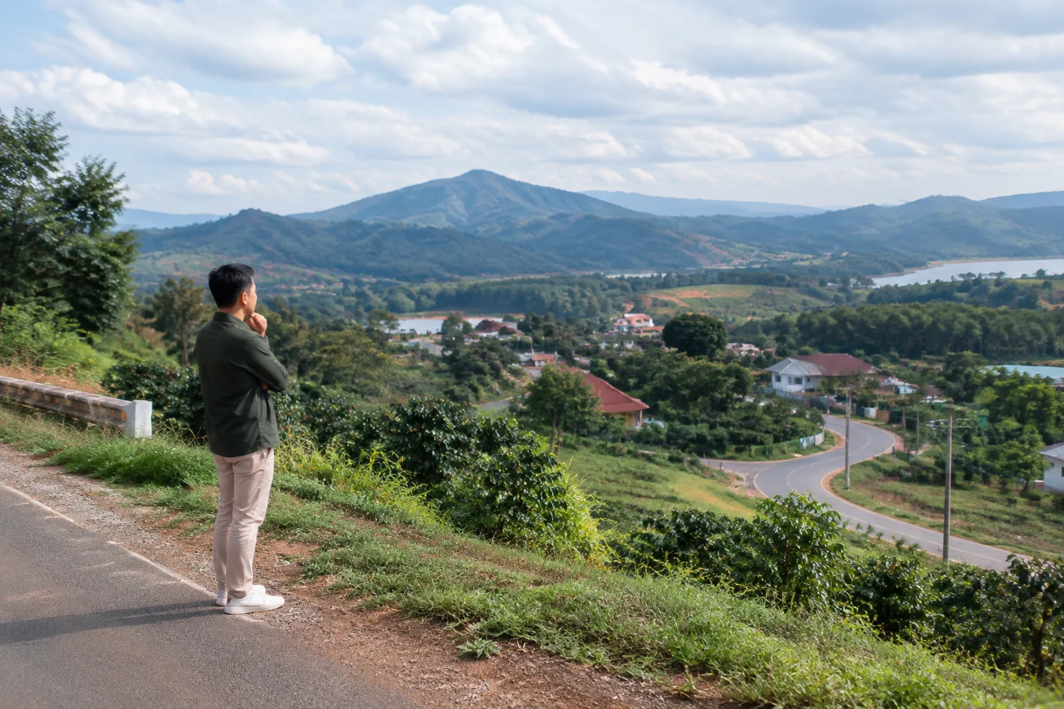 Người mua lần đầu đang quan sát khu vực dân cư và cảnh quan Đắk Nông từ một điểm dừng ven đường, thể hiện giai đoạn tìm hiểu nhu cầu và lựa chọn khu vực trước khi tìm tài sản cụ th